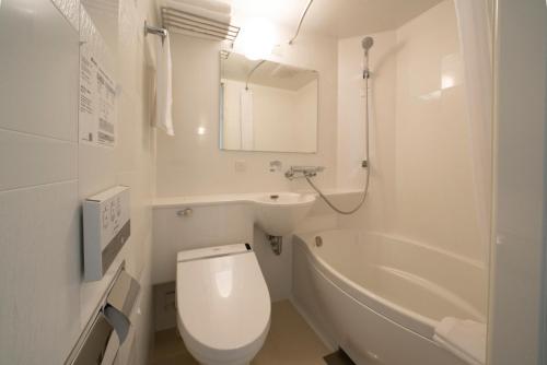 a white bathroom with a toilet and a bath tub at Hotel Meriken Port Kobe Motomachi in Kobe