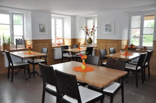 a restaurant with wooden tables and chairs and windows at Le Relais du Château Monney in Cournillens