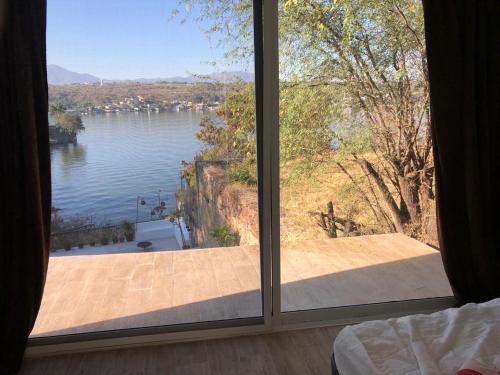 a bedroom with a large window looking out at a lake at Experiencia Teques in Tequesquitengo