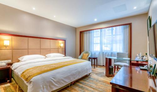 a hotel room with a large bed and a desk at Yantai Meiya International ApartHotel (Previous Ramada Plaza) in Yantai