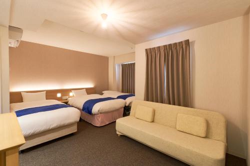 a hotel room with two beds and a couch at Hotel Meriken Port Kobe Motomachi in Kobe