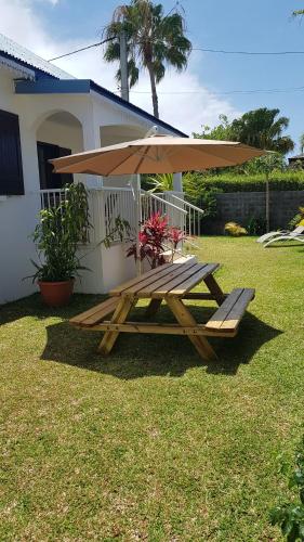 a wooden picnic table with an umbrella in a yard at Villa Créole Alamanda in Petite Île