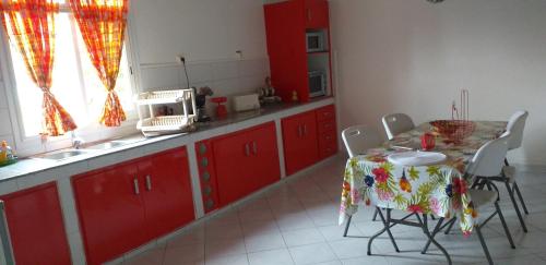 een keuken met rode kasten en een tafel met stoelen bij VILLA MALOU chez Maryse in Bouillante