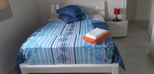 een bed met een blauw en wit dekbed en handdoeken erop bij VILLA MALOU chez Maryse in Bouillante