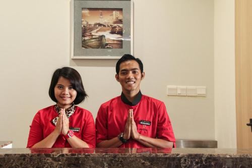 a man and a woman sitting at a counter praying at Dreamtel Jakarta in Jakarta