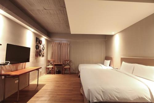 a hotel room with two beds and a desk and a television at Tourism Inn in Yongkang
