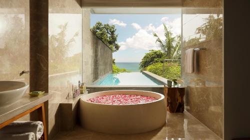 a bathroom with a tub with a view of a pool at Maya Sanur Resort & Spa in Sanur