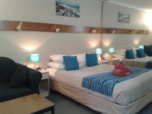 um quarto com 2 camas com almofadas azuis e vermelhas em Elsinor Motor Lodge em Wollongong