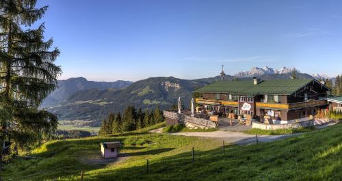 una gran casa en una colina con montañas en el fondo en Angerer Alm, en Sankt Johann in Tirol