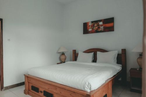 a bedroom with a bed with white sheets and two lamps at Sekar Arum Riverside Resort in Canggu in Tanah Lot