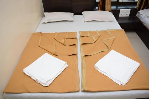 two beds with brown sheets and white pillows on them at Hotel Sai Sampada NX in Shirdi
