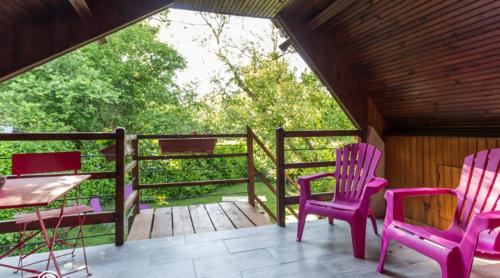 a porch with pink chairs and a table on a porch at les riflets in Conches-en-Ouche