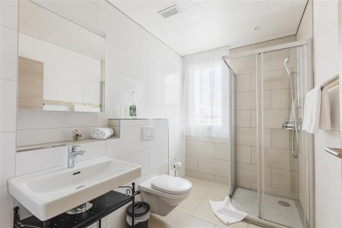 Aparthotel Wiggertal - Self Check-in في Dagmersellen: حمام أبيض مع حوض ومرحاض