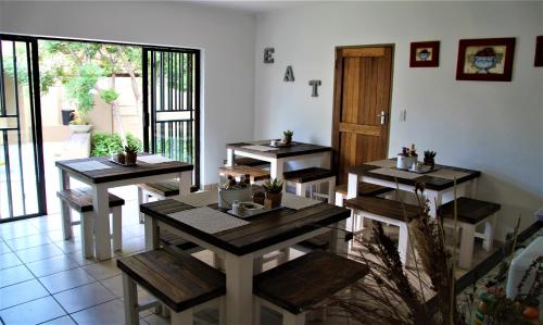 a restaurant with wooden tables and chairs in a room at Mahem Manor Guesthouse in Brits