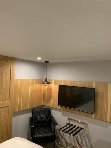 a room with a chair and a television on a wall at PAPO'A Hotel in Kaohsiung