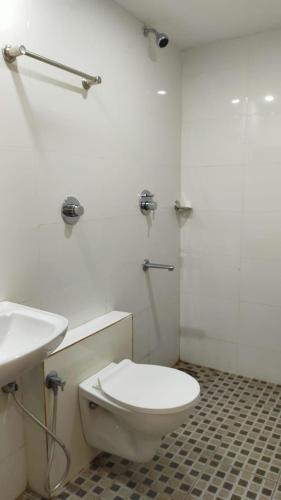 a white bathroom with a toilet and a sink at Bhumi Residency in Mangalore