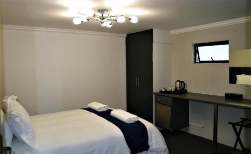 a bedroom with a bed and a desk with towels at Mahem Manor Guesthouse in Brits