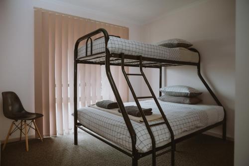 a bunk bed in a room with a chair at Alkoomi Chalets in Frankland