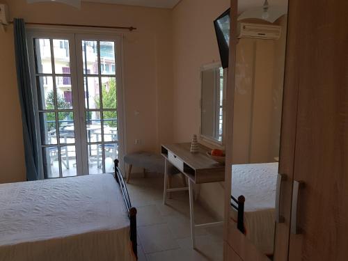 a bedroom with two beds and a desk and a window at Nefeli Wind Club in Vasiliki