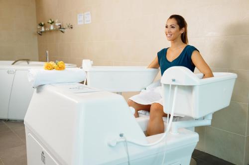 a woman sitting on a toilet in a bathroom at Hotel Premier Aqua - Adults Only in Vrdnik