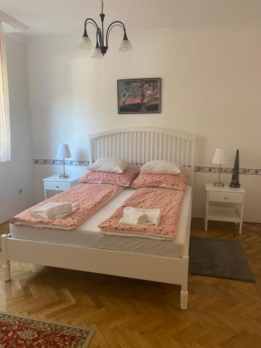 1 dormitorio con 1 cama con sábanas rosas y 2 mesas en Pálma apartman, en Szentes