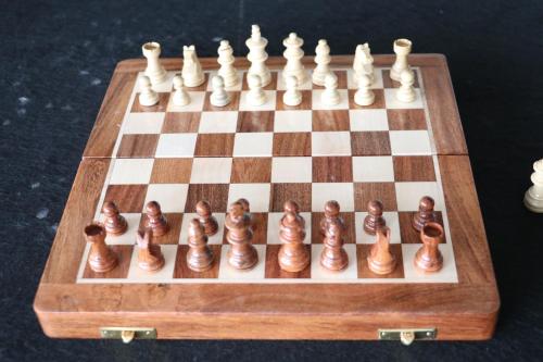 a wooden chess board with a chess set on it at The Soni'otel in Hāora