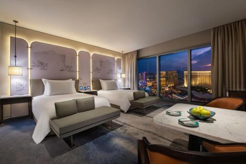 um quarto de hotel com uma cama grande e uma mesa e um quarto com vista em City of Dreams Macau - Nüwa Macau em Macau