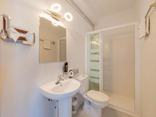 a bathroom with a sink, toilet and mirror at Hostal Port Corona in Cala Ratjada