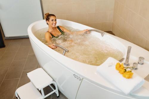 a woman in a bath tub with water at Hotel Premier Aqua - Adults Only in Vrdnik
