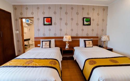 a hotel room with two beds and two lamps at Hoang Hai Hotel in Hai Phong