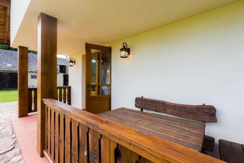 a wooden bench sitting on the side of a porch at Dolina Biebrzy - Chata Retmana in Wroceń