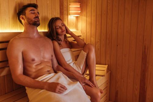 a man and a woman sitting in a sauna at Hotel Premier Aqua - Adults Only in Vrdnik