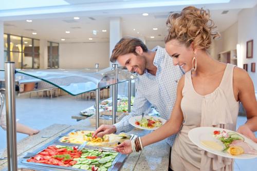 a man and a woman preparing food at a buffet at Hotel Interferie Medical SPA in Świnoujście