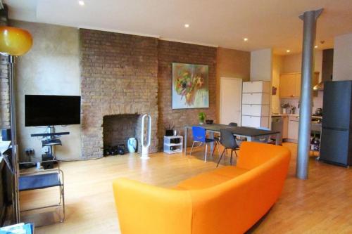 ロンドンにあるGuestReady - Bright Studio in the Heart of Londonのリビングルーム(オレンジ色のソファ、暖炉付)