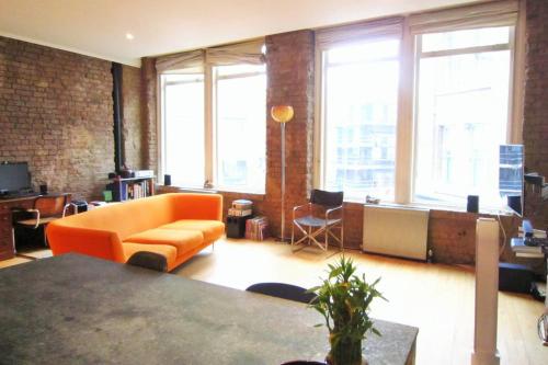 ロンドンにあるGuestReady - Bright Studio in the Heart of Londonのリビングルーム(オレンジ色のソファ、一部の窓付)