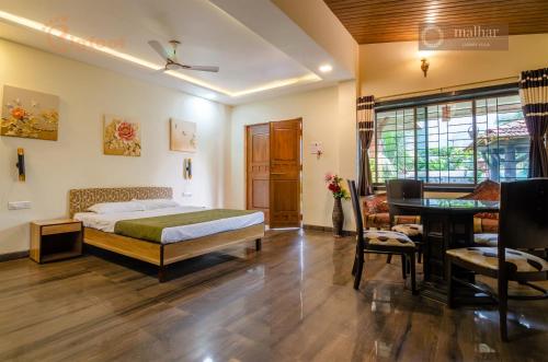 a bedroom with a bed and a desk and a table at Malhar Villa -Kashid in Kashid