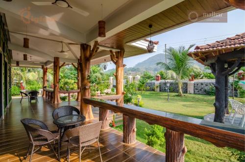 a porch of a house with chairs and a table at Malhar Villa -Kashid in Kashid