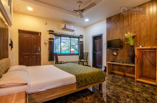 a hotel room with a bed and a tv at Malhar Villa -Kashid in Kashid