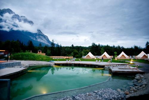 a pool of water with a mountain in the background at Gerhardhof - Zimmer Glamping Camping in Wildermieming