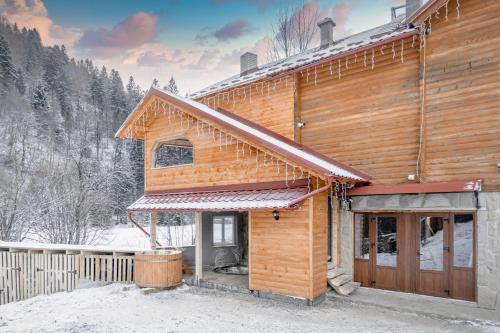ein Blockhaus mit Schnee auf dem Boden in der Unterkunft Villa Ladna Tatariv Bukovel in Tatariw