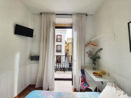 a room with a bed and a window with a table at Hostal Alicante in Madrid