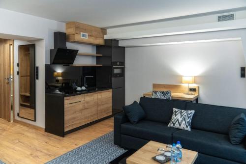 a living room with a couch and a kitchen at Hotel Meta Resort & Vine SPA in Szczyrk
