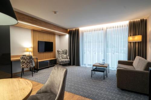 a living room with a couch and a tv in a hotel room at Hotel Meta Resort & Vine SPA in Szczyrk