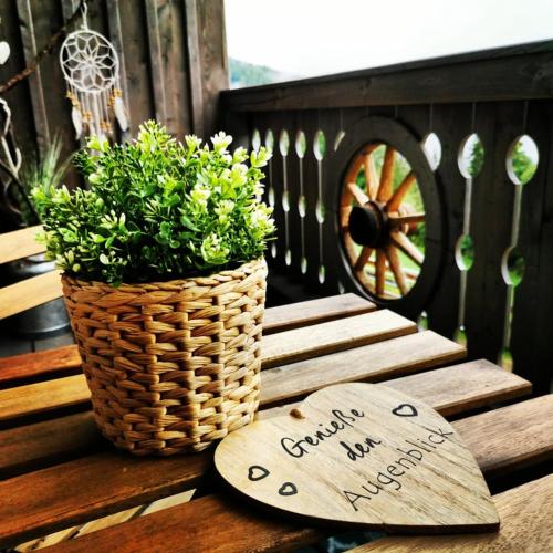 a plant in a basket and a sign on a bench at Erlebnisbauernhof Gutschi Ranch in Kamp