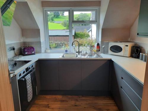 a kitchen with a sink and a microwave at 3 Bed Barn - Sleeps up to 6 - Parking - Wifi in Hawkshead