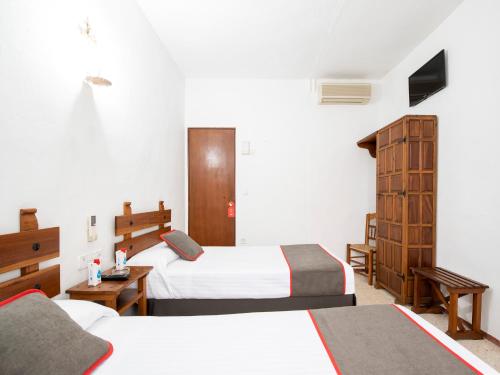 エシハにあるHostal Santiagoのベッド2台とデスクが備わるホテルルームです。