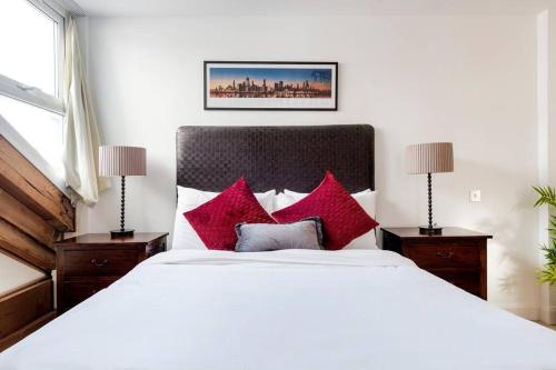 um quarto com uma grande cama branca com almofadas vermelhas em Penthouse Loft apartment with roof terrace Not for events or parties em Londres