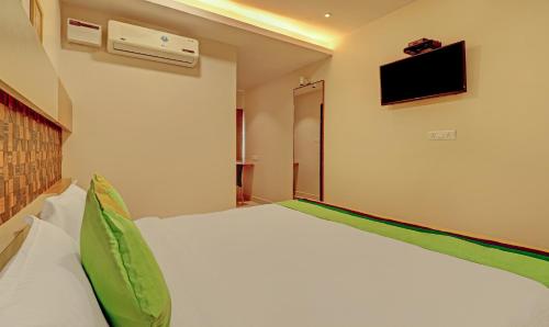 a bedroom with a white bed and a tv on the wall at Treebo Rainbow Grand in Visakhapatnam
