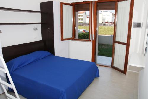 Un dormitorio con una cama azul y una ventana en Residence Equilio Family Apartments, en Lido di Jesolo