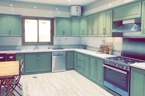 a kitchen with green cabinets and a stove top oven at Luxury fully furnished villa ڤيلا مؤثثة in AlUla